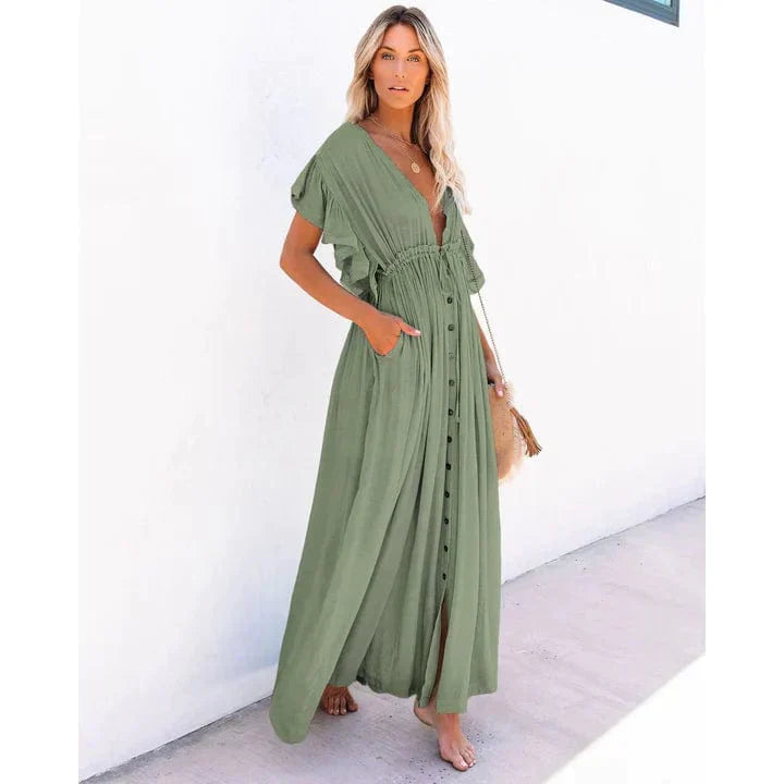 Woman wearing the Sage Women's Button-Down Maxi Dress, a long, flowy dress with a relaxed fit, button-down front, and functional side pockets, styled with a casual boho-chic look, holding a woven bag and posing outdoors against a simple background.