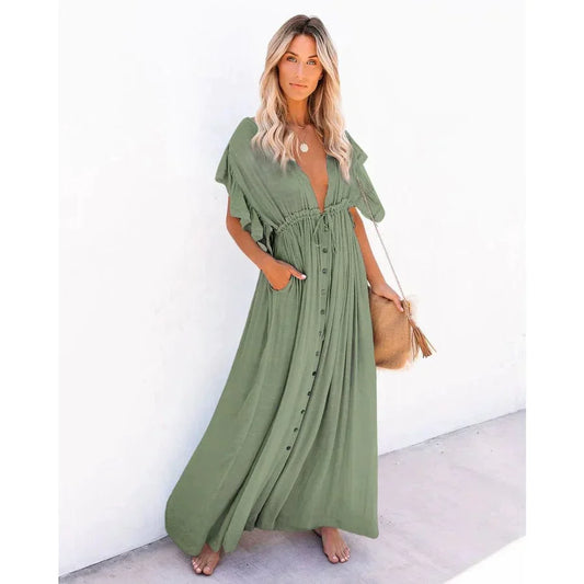 Woman wearing the Sage Women's Button-Down Maxi Dress, a long, flowy dress with a relaxed fit, button-down front, and functional side pockets, styled with a casual boho-chic look, holding a woven bag and posing outdoors against a simple background.