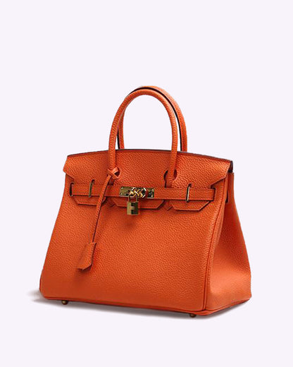 Image showing a woman holding an elegant handbag with a sleek design, featuring gold hardware and a structured shape, paired with casual attire for a stylish, sophisticated look.