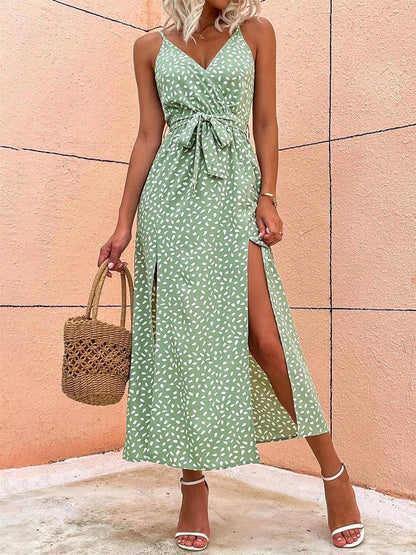 A woman wearing the Elara Women's Summer Wrap Dress with a sleeveless, wrap design, tied waist, and elegant side slits. This stylish and lightweight dress is perfect for warm weather, accessorized with a woven handbag and strappy heels for a chic summer look.