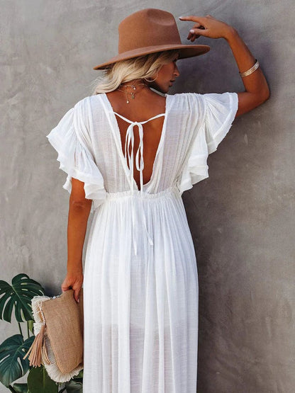 Woman wearing a wide-brimmed hat and accessorized with layered necklaces, modeling the Ivy | Flowing Bohemian Maxi Dress in an outdoor setting surrounded by natural scenery, emphasizing the dress's relaxed fit, airy fabric, and bohemian style.