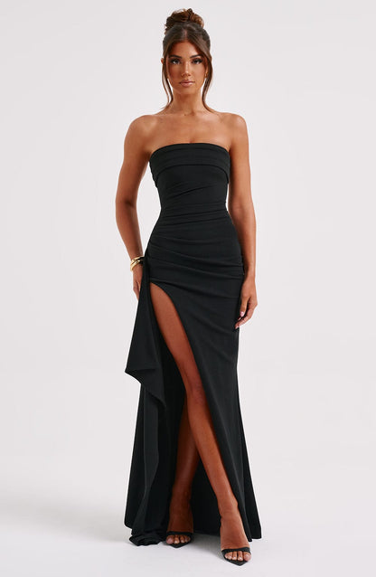 A woman wearing an elegant strapless gown with a fitted bodice and a high slit, creating a chic and sophisticated look. The dress flows gracefully to the floor, perfect for formal events and upscale parties. She pairs it with high heels and minimal accessories for a timeless style.