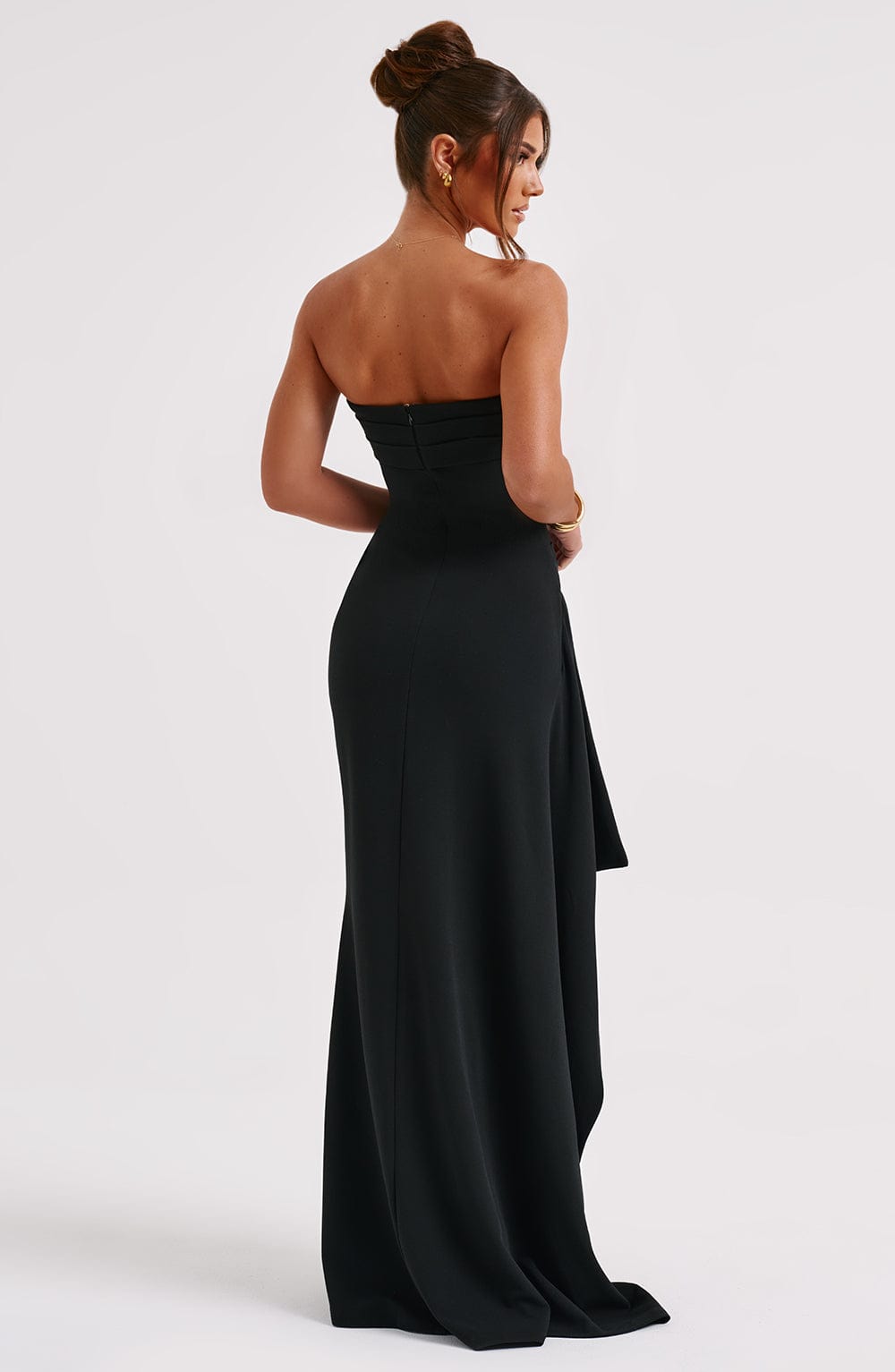 A woman wearing an elegant strapless gown with a fitted bodice and a high slit, creating a chic and sophisticated look. The dress flows gracefully to the floor, perfect for formal events and upscale parties. She pairs it with high heels and minimal accessories for a timeless style.