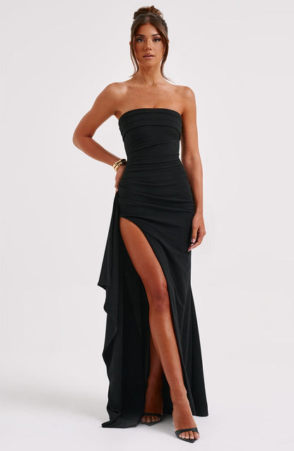 A woman wearing an elegant strapless gown with a fitted bodice and a high slit, creating a chic and sophisticated look. The dress flows gracefully to the floor, perfect for formal events and upscale parties. She pairs it with high heels and minimal accessories for a timeless style.